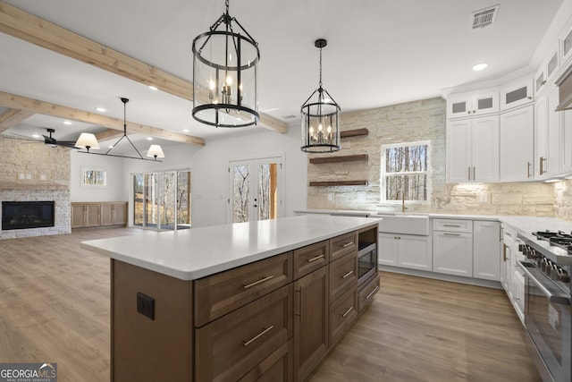 kitchen featuring a sink, white cabinets, light countertops, a center island, and pendant lighting