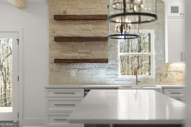 kitchen with white cabinets, an inviting chandelier, light countertops, open shelves, and a sink