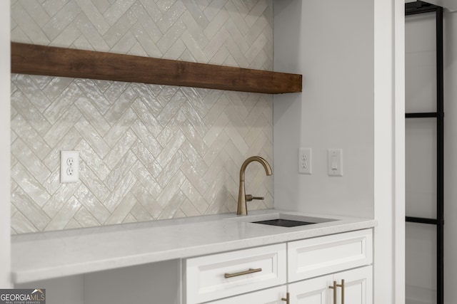 interior details featuring light stone countertops, wet bar, white cabinetry, open shelves, and a sink