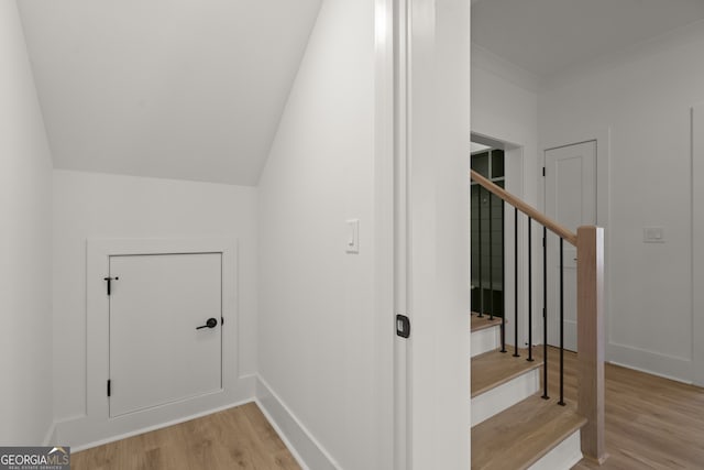 stairway with crown molding, baseboards, and wood finished floors