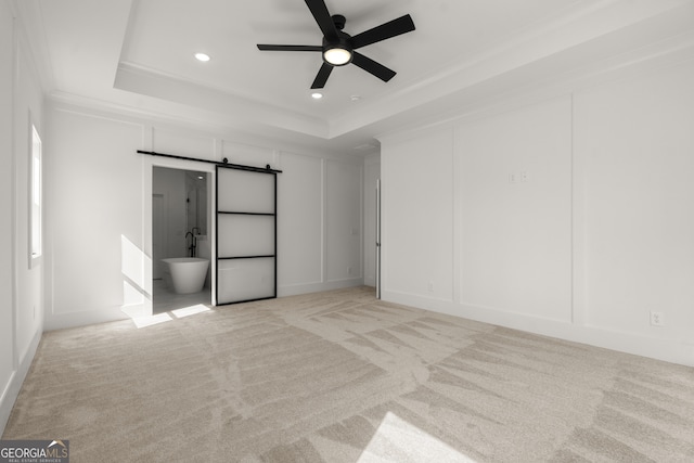 unfurnished bedroom with recessed lighting, a raised ceiling, light colored carpet, and a decorative wall