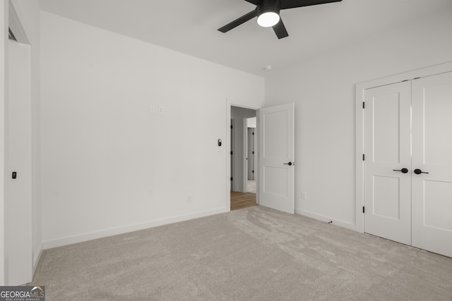 unfurnished bedroom featuring a ceiling fan, a closet, light colored carpet, and baseboards