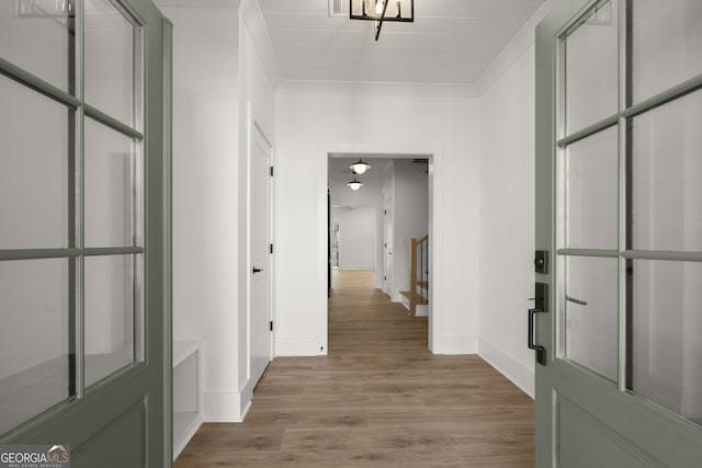 hallway featuring light wood-type flooring, stairway, baseboards, and ornamental molding