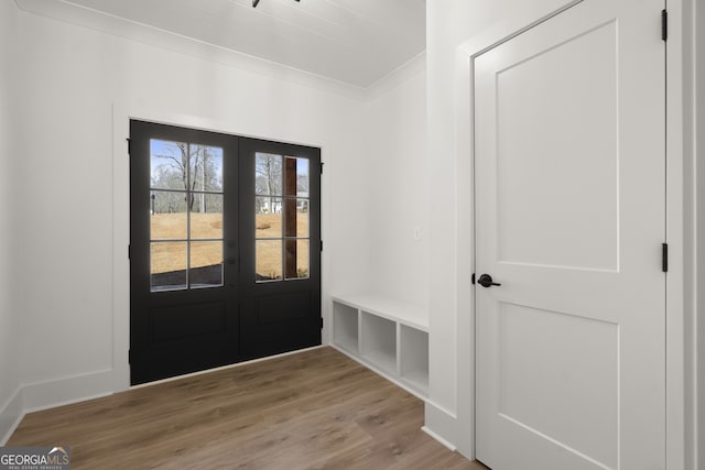 entryway featuring ornamental molding, light wood-type flooring, and french doors