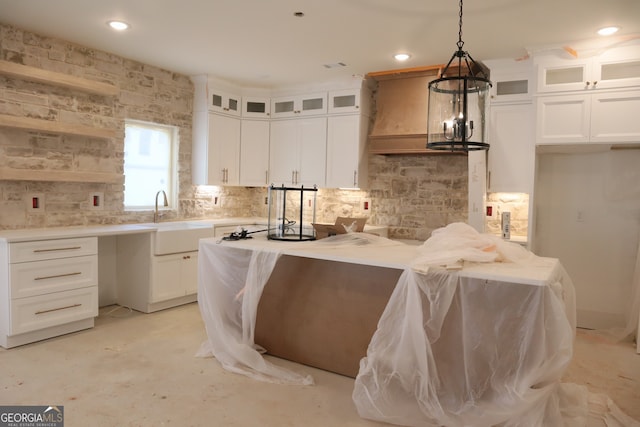 kitchen featuring light countertops, hanging light fixtures, glass insert cabinets, white cabinets, and a sink