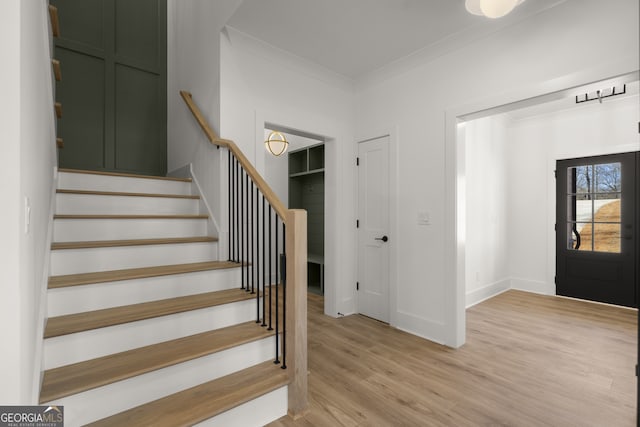 foyer entrance with stairs, ornamental molding, light wood-type flooring, and baseboards