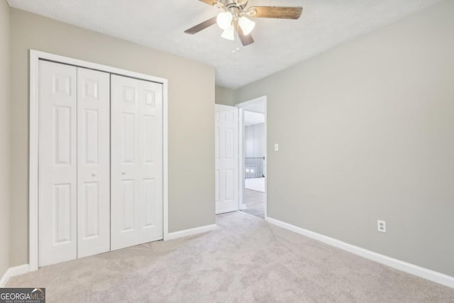 unfurnished bedroom featuring ceiling fan, a closet, and light carpet