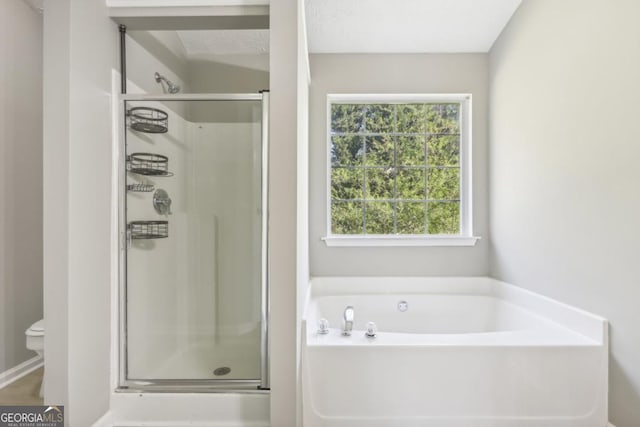 bathroom with toilet, a healthy amount of sunlight, and shower with separate bathtub