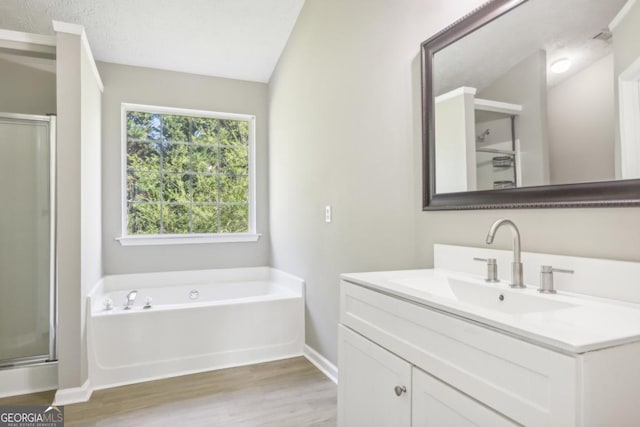 bathroom featuring hardwood / wood-style floors, vanity, vaulted ceiling, and shower with separate bathtub