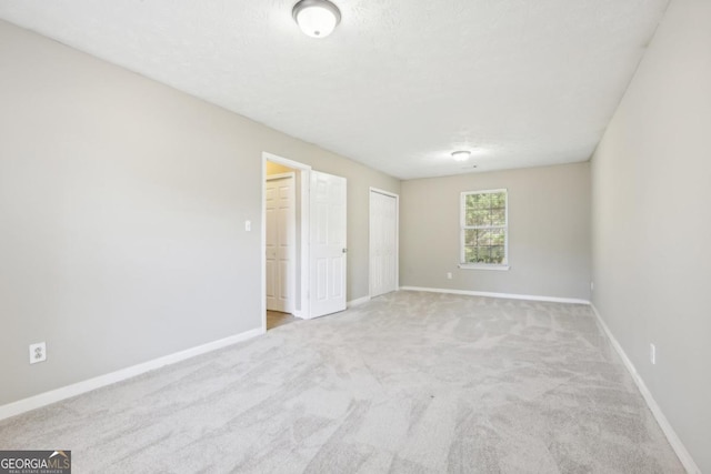 unfurnished bedroom with light colored carpet and a textured ceiling