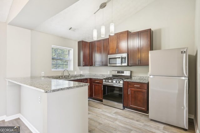 kitchen featuring sink, hanging light fixtures, light wood-type flooring, kitchen peninsula, and stainless steel appliances