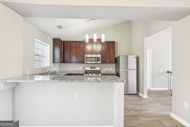 kitchen featuring sink, light stone countertops, decorative light fixtures, kitchen peninsula, and stainless steel appliances