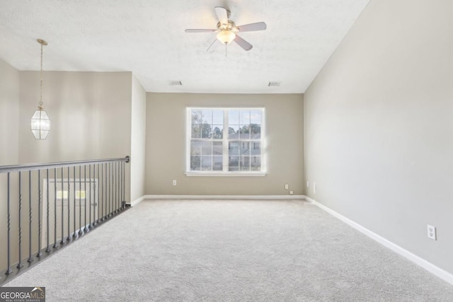 empty room with ceiling fan, carpet floors, and a textured ceiling