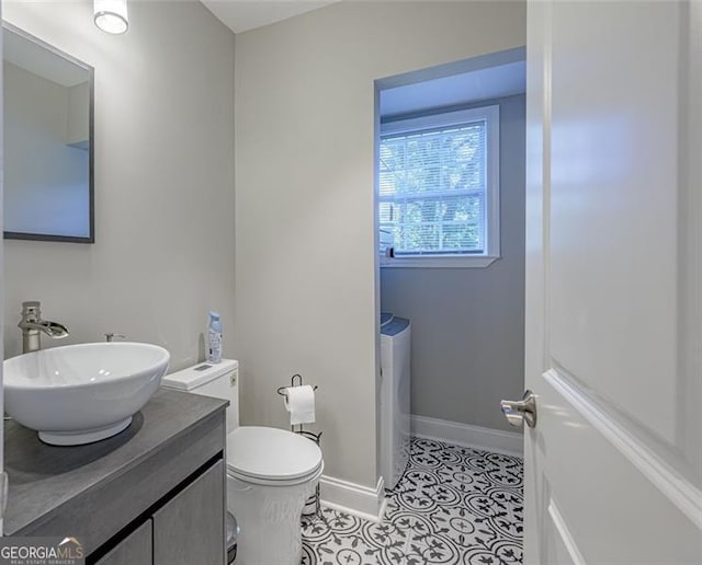 bathroom featuring washing machine and clothes dryer, tile patterned floors, vanity, and toilet