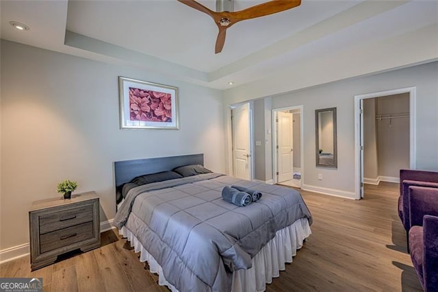 bedroom with a raised ceiling, ceiling fan, a closet, and a spacious closet