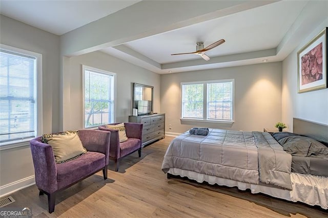 bedroom featuring a tray ceiling, ceiling fan, and light wood-type flooring