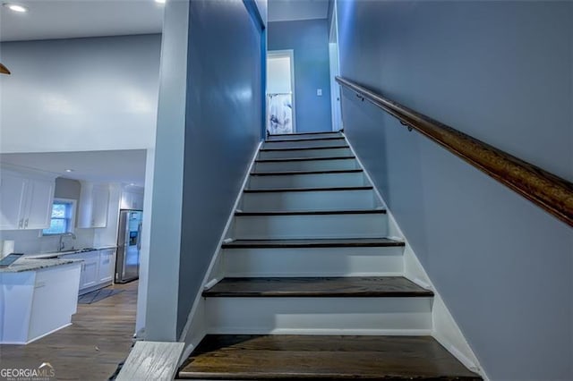 staircase with hardwood / wood-style floors and sink