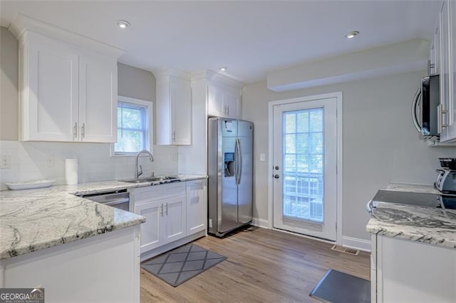 kitchen featuring white cabinets, sink, light wood-type flooring, light stone counters, and stainless steel appliances