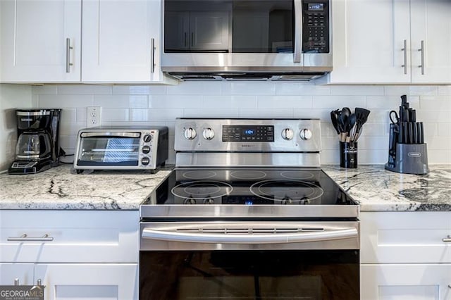 kitchen featuring backsplash, light stone countertops, white cabinets, and stainless steel appliances