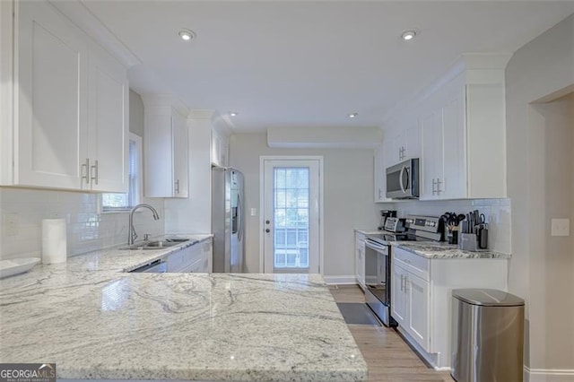 kitchen featuring light stone counters, sink, white cabinets, and appliances with stainless steel finishes