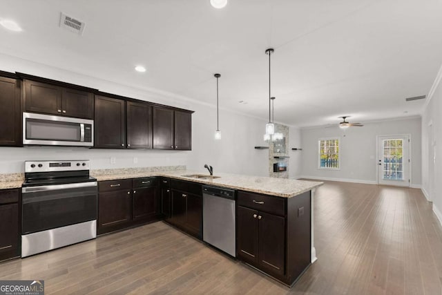 kitchen with dark brown cabinetry, ceiling fan, crown molding, decorative light fixtures, and appliances with stainless steel finishes