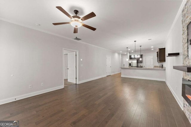 unfurnished living room with ceiling fan, dark hardwood / wood-style flooring, crown molding, and a fireplace