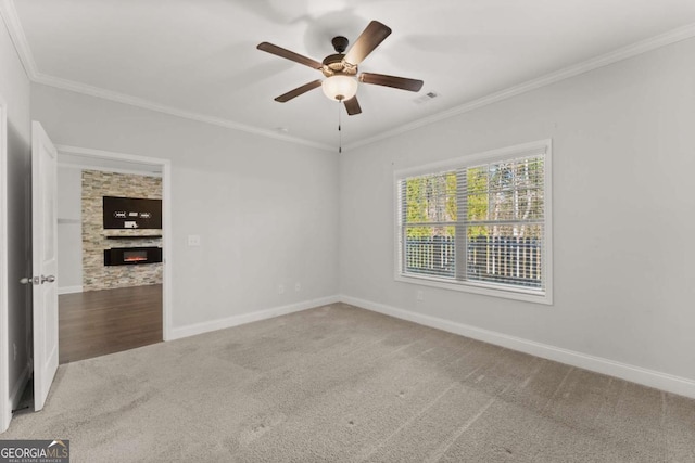 carpeted empty room featuring ceiling fan, ornamental molding, and a fireplace