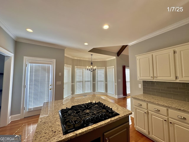 kitchen featuring backsplash, black gas stovetop, decorative light fixtures, white cabinets, and a chandelier