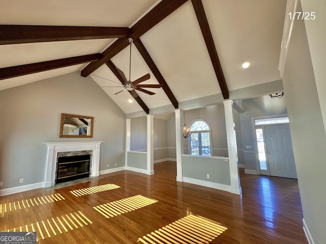 unfurnished living room featuring a high end fireplace, dark hardwood / wood-style flooring, decorative columns, ceiling fan, and vaulted ceiling with beams