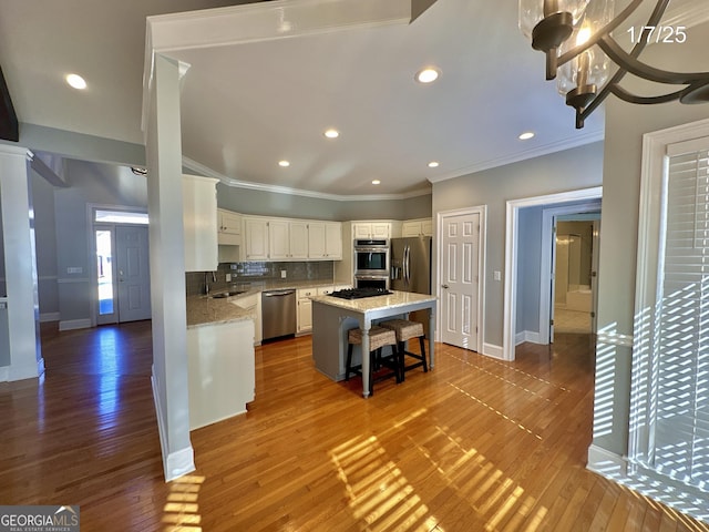 kitchen with a center island, white cabinets, a breakfast bar area, wood-type flooring, and stainless steel appliances