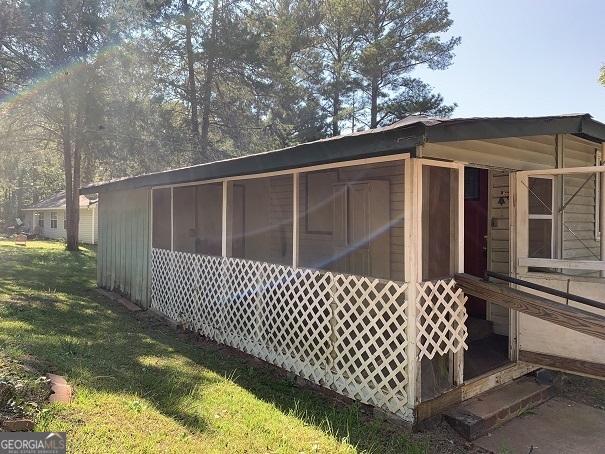 view of property exterior with a sunroom and a yard