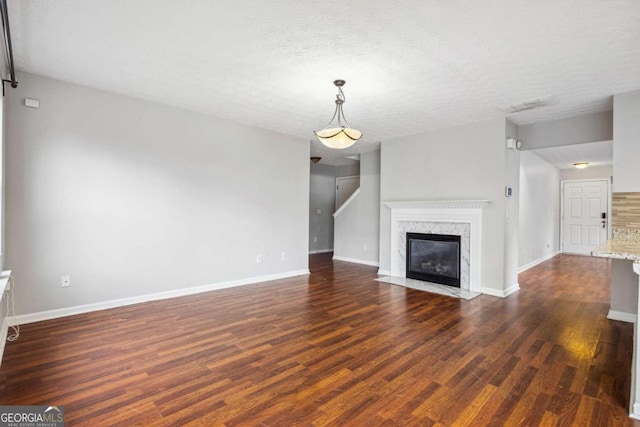 unfurnished living room with dark hardwood / wood-style flooring, a high end fireplace, and a textured ceiling