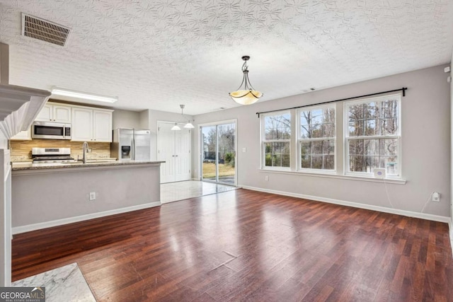 unfurnished living room with sink, dark hardwood / wood-style flooring, and a textured ceiling