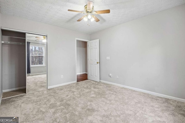 unfurnished bedroom with carpet, a textured ceiling, a closet, and ceiling fan