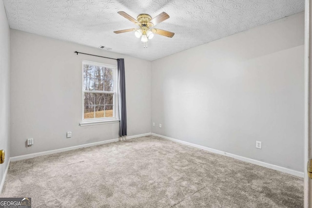 empty room with carpet flooring, ceiling fan, and a textured ceiling