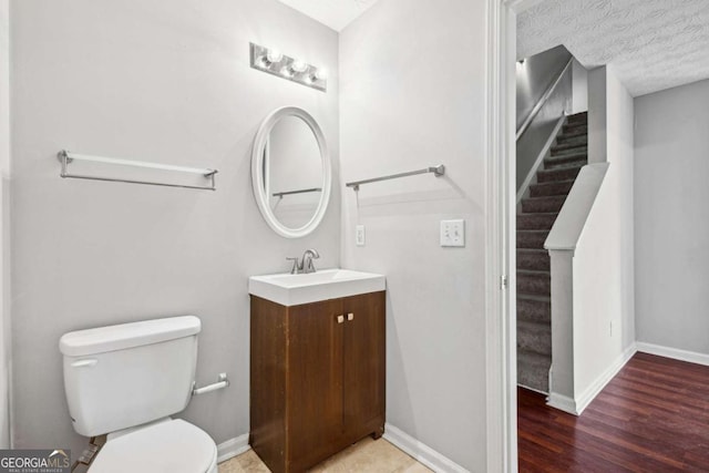 bathroom featuring hardwood / wood-style flooring, vanity, a textured ceiling, and toilet