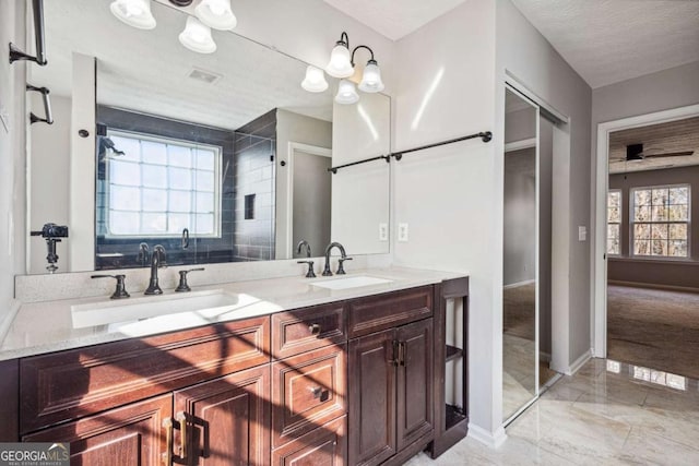 bathroom with ceiling fan, plenty of natural light, a textured ceiling, and vanity