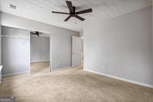 unfurnished bedroom featuring carpet, ceiling fan, a textured ceiling, and a closet