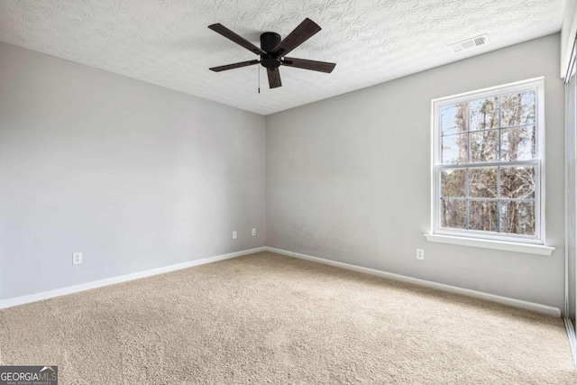 carpeted empty room featuring baseboards, a textured ceiling, visible vents, and a ceiling fan