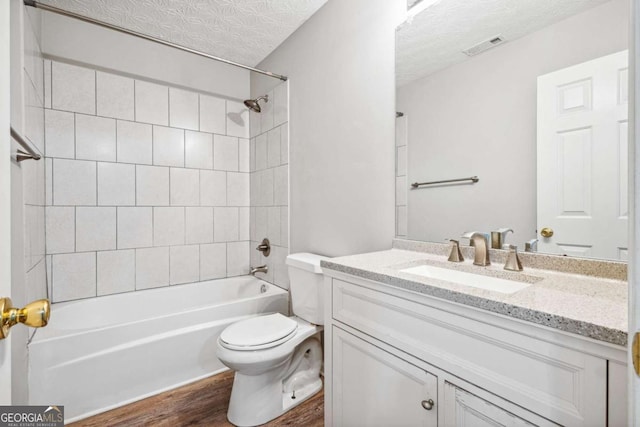 bathroom with shower / bathtub combination, visible vents, toilet, a textured ceiling, and vanity