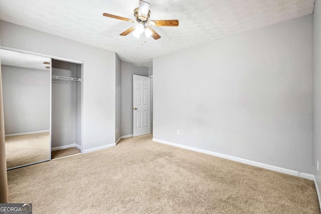 unfurnished bedroom with carpet, a textured ceiling, a closet, and ceiling fan