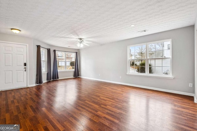 interior space with a textured ceiling, ceiling fan, and dark wood-type flooring