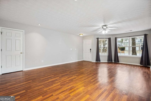 unfurnished living room featuring a textured ceiling, wood finished floors, visible vents, a ceiling fan, and baseboards