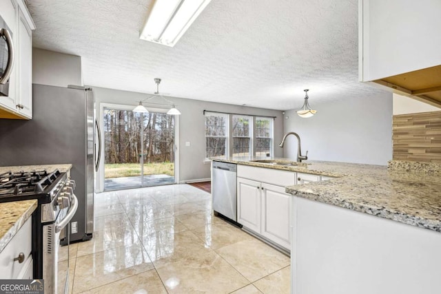 kitchen with pendant lighting, sink, a wealth of natural light, white cabinetry, and stainless steel appliances