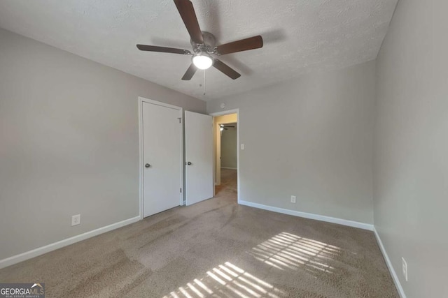 unfurnished bedroom with ceiling fan, light colored carpet, and a textured ceiling