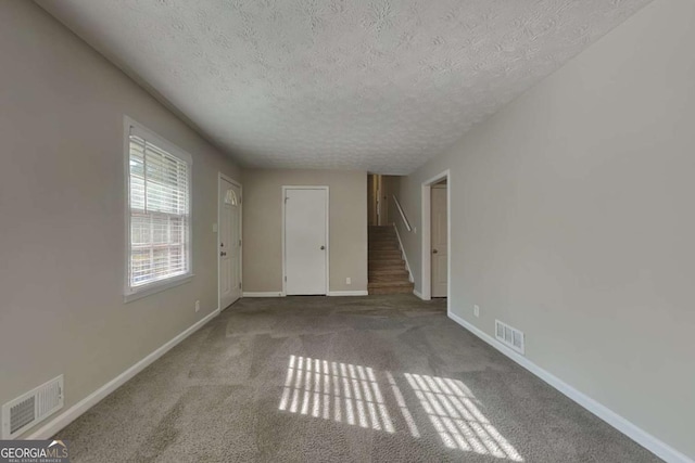 unfurnished room with light colored carpet and a textured ceiling