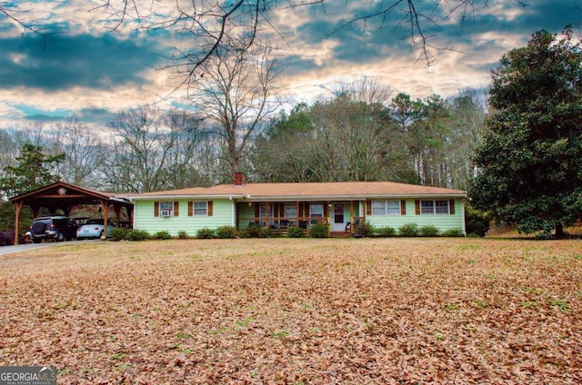 ranch-style home featuring a lawn and a carport