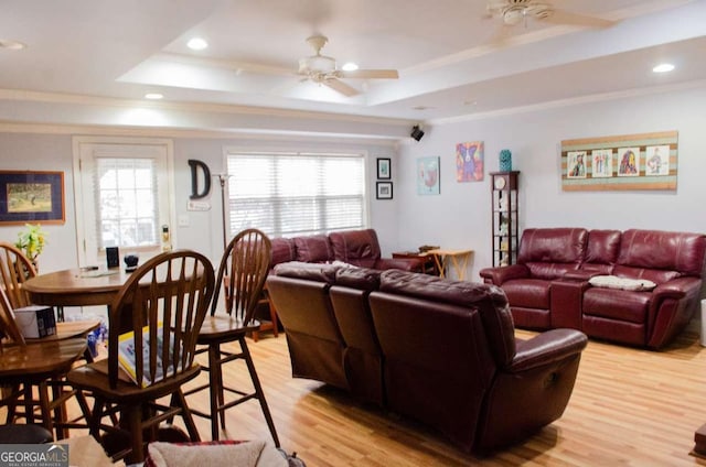 living room featuring a raised ceiling, ceiling fan, light hardwood / wood-style floors, and ornamental molding