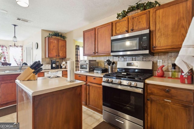 kitchen featuring stainless steel appliances, backsplash, pendant lighting, a textured ceiling, and a center island with sink