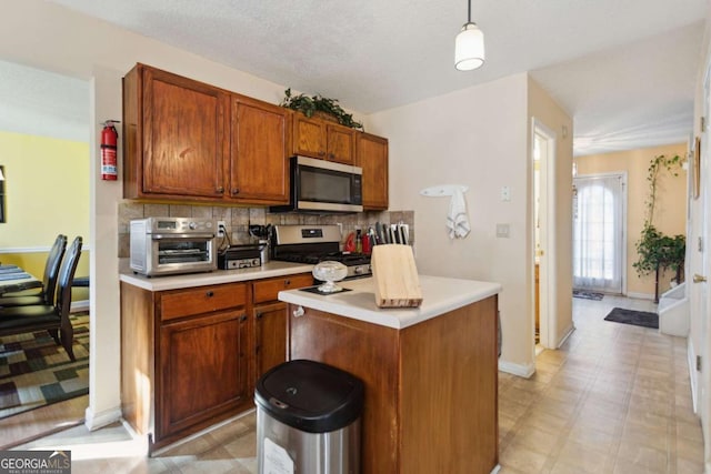 kitchen featuring pendant lighting, a kitchen island, appliances with stainless steel finishes, and tasteful backsplash